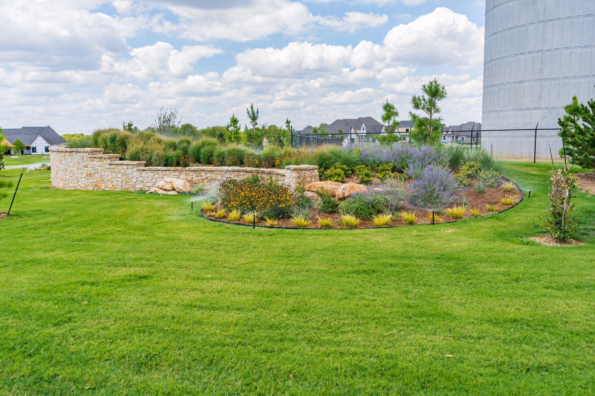 Wide green lawn with a landscaped berm of shrubs and grasses