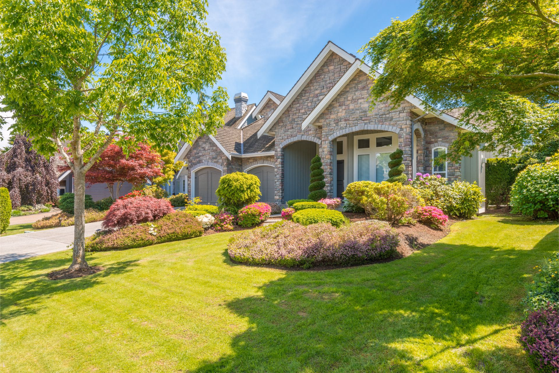 Stone house with a landscaped front yard and green lawn